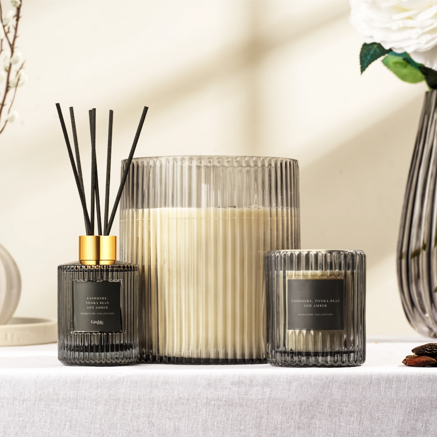Collection of black soy wax candles and a natural oil diffuser set on a table with decorative elements