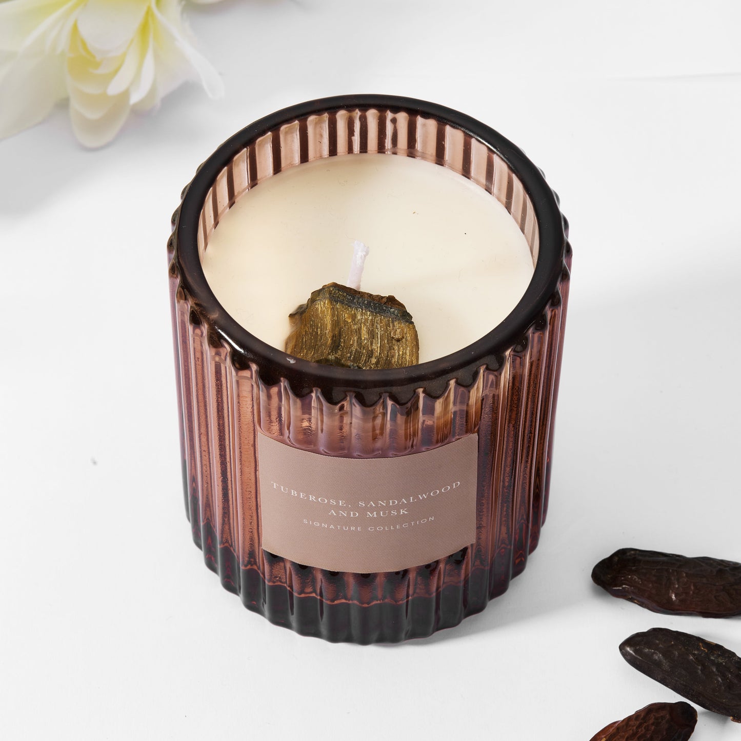 Soy wax amber candle in ribbed glass with raw tiger's eye gemstone.