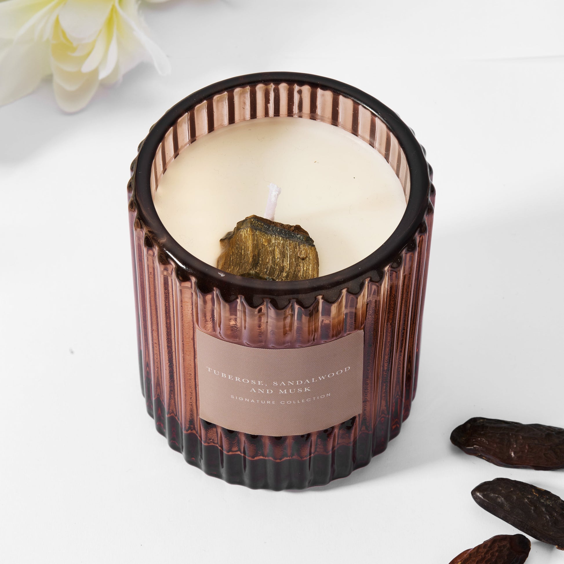 Soy wax amber candle in ribbed glass with raw tiger's eye gemstone.