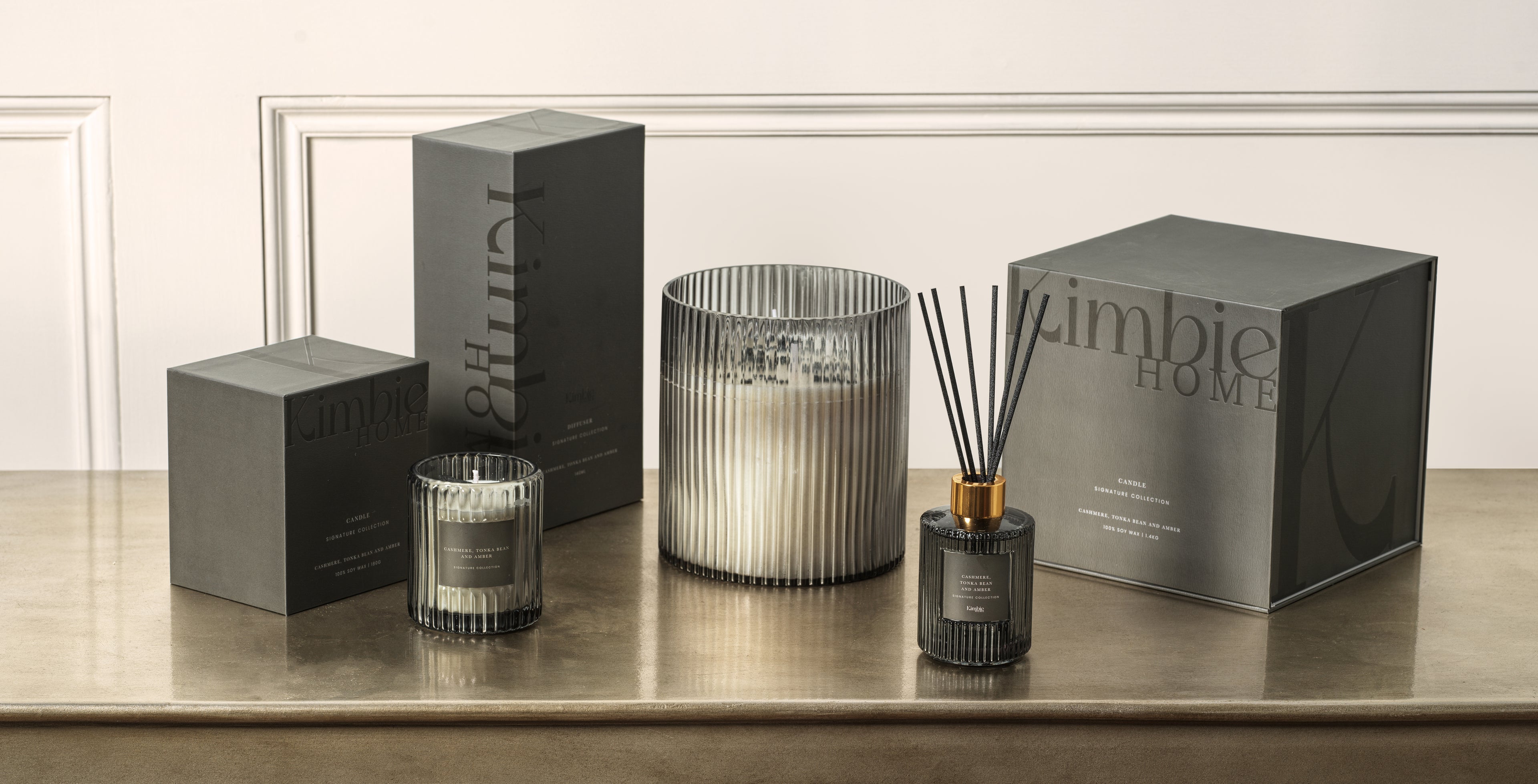 Kimbie Home products including soy wax candles and natural oil diffusers on a wooden surface.