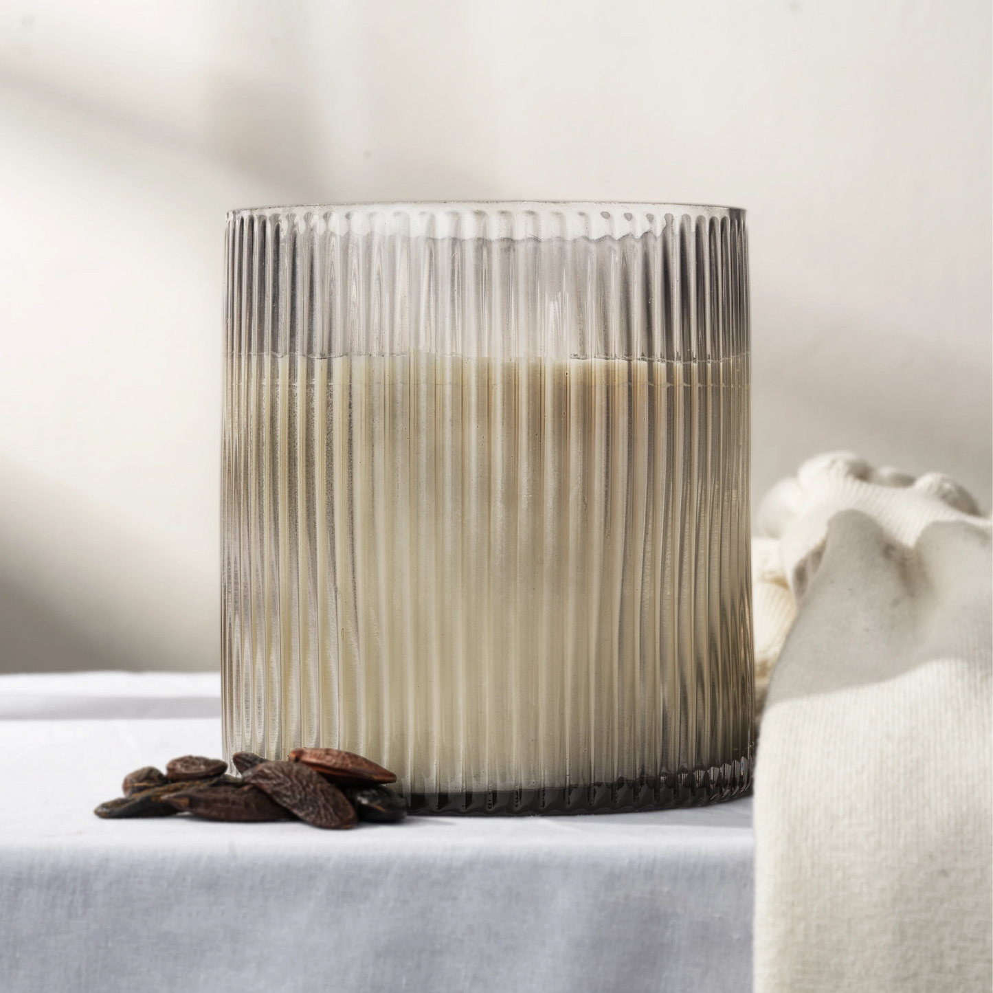 Black ribbed glass soy wax candle on a light surface