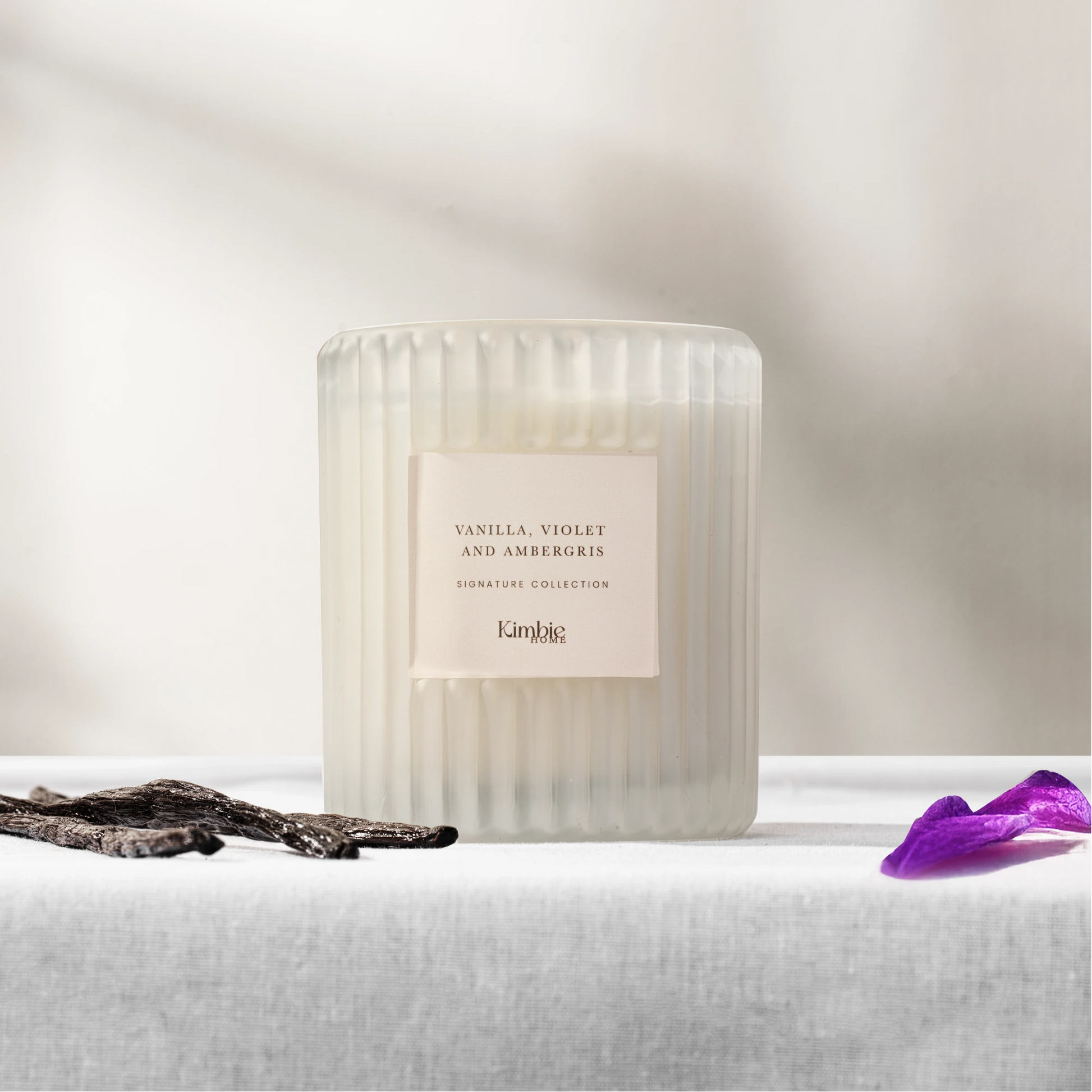 White ribbed glass soy wax candle on a white surface and light grey background