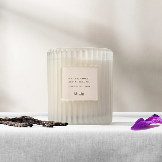 White ribbed glass soy wax candle on a white surface and light grey background